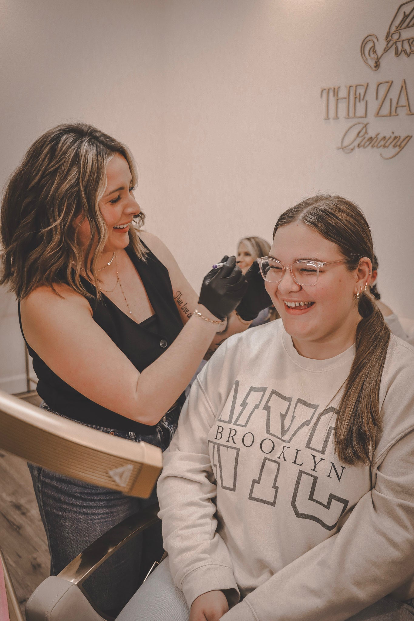 Woman getting a Ear Piercing from another woman in a salon setting.